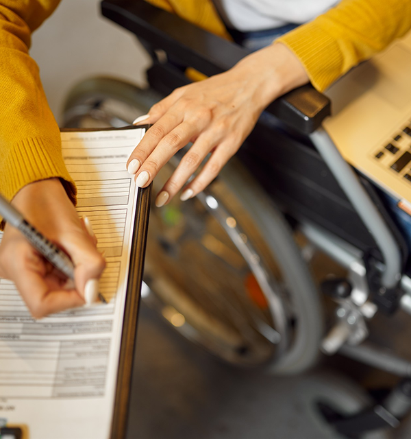 a hand of a woman writing while sitting on the wheelchair