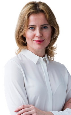 a woman with a short wavy blonde hair wearing a white long sleeve polo